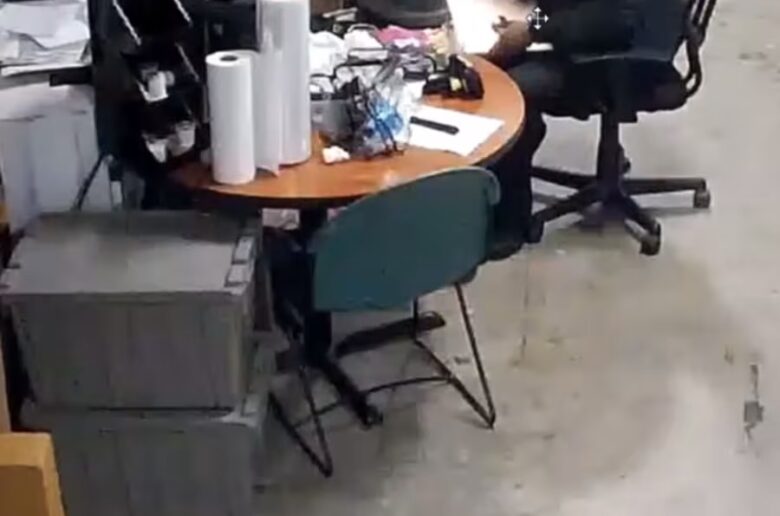 a man sitting at a round table in a room with a lot of boxes