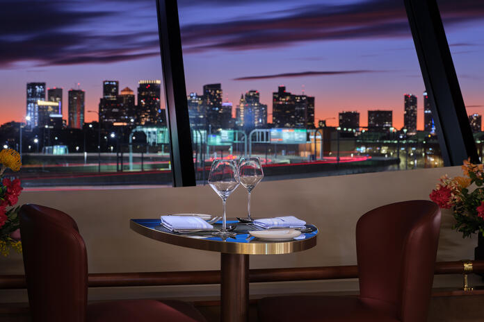 a table with wine glasses and napkins on it with a city view in the background