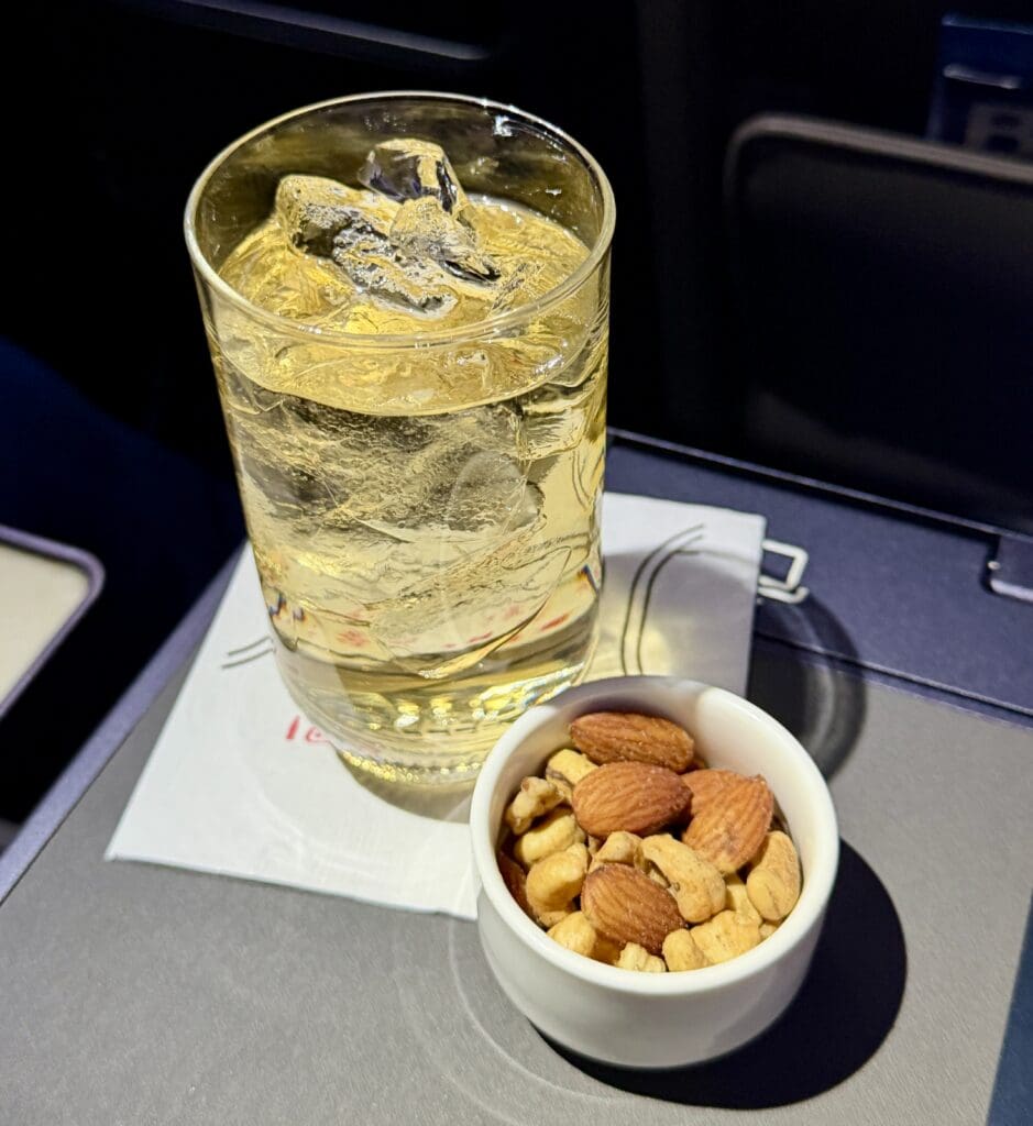 a glass of liquid and a bowl of nuts