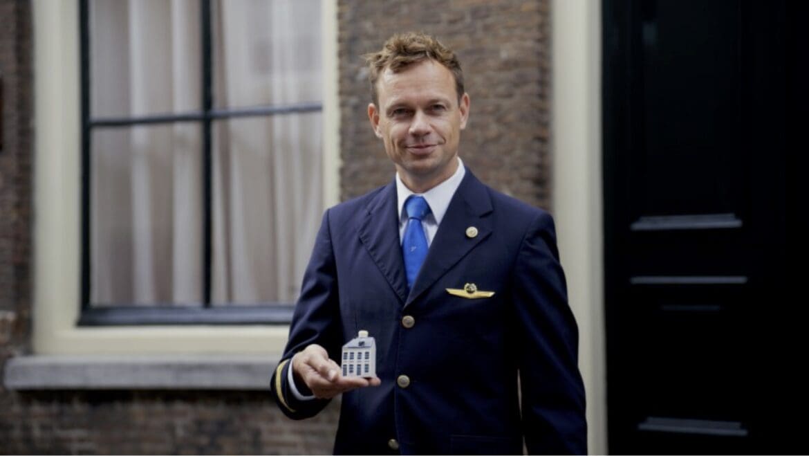 KLM 106 3 a man in a suit holding a small model of a house