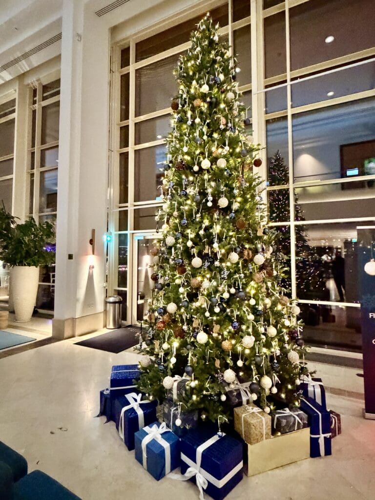 a christmas tree with presents in front of a large window